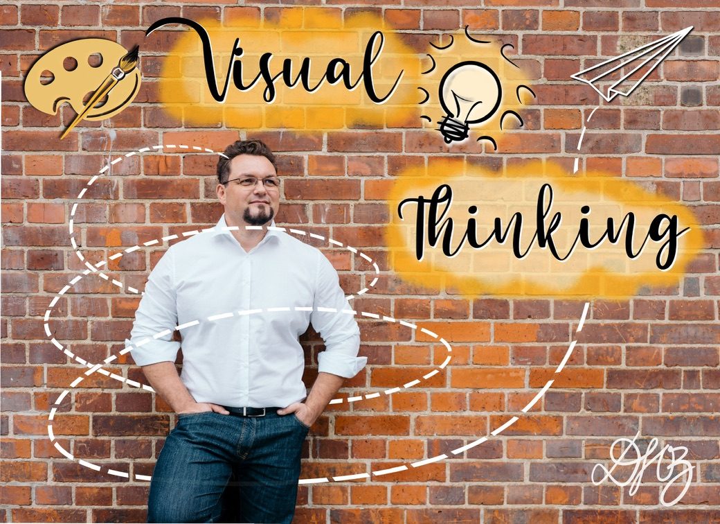 Danny Herzog-Braune vor einer Backsteinwand mit gezeichnetem Schriftzug Visual Thinking